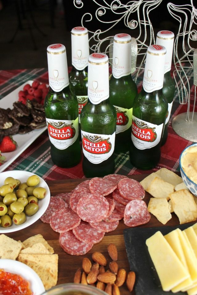 several bottles of beer, cheeses and crackers on a table with plates of food