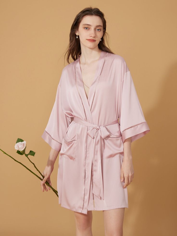 Step into a realm of pure elegance and beauty with our Graceful Hollow Detail Short Robe Collectio. As you slip into one of these robes, you'll instantly feel enveloped in luxury and sophistication, each delicate fold and intricate hollow detail designed to accentuate your grace and allure. Skin-Friendly Fabric: Crafted from the finest silky fabric, these robes offer an unparalleled sensation of comfort against your skin, promising a luxurious experience with every wear. Their unique hollow deta Elegant V-neck Robe For Daywear, Elegant Open Front Night Dresses, Elegant Sleepwear With Kimono Sleeves For Loungewear, Elegant Night Robe With V-neck, Elegant Spring Sleep Robe, Elegant Summer Wrap Sleepwear, Satin V-neck Robe For Daywear, Elegant Pink V-neck Kimono, Elegant V-neck Robe In Solid Color