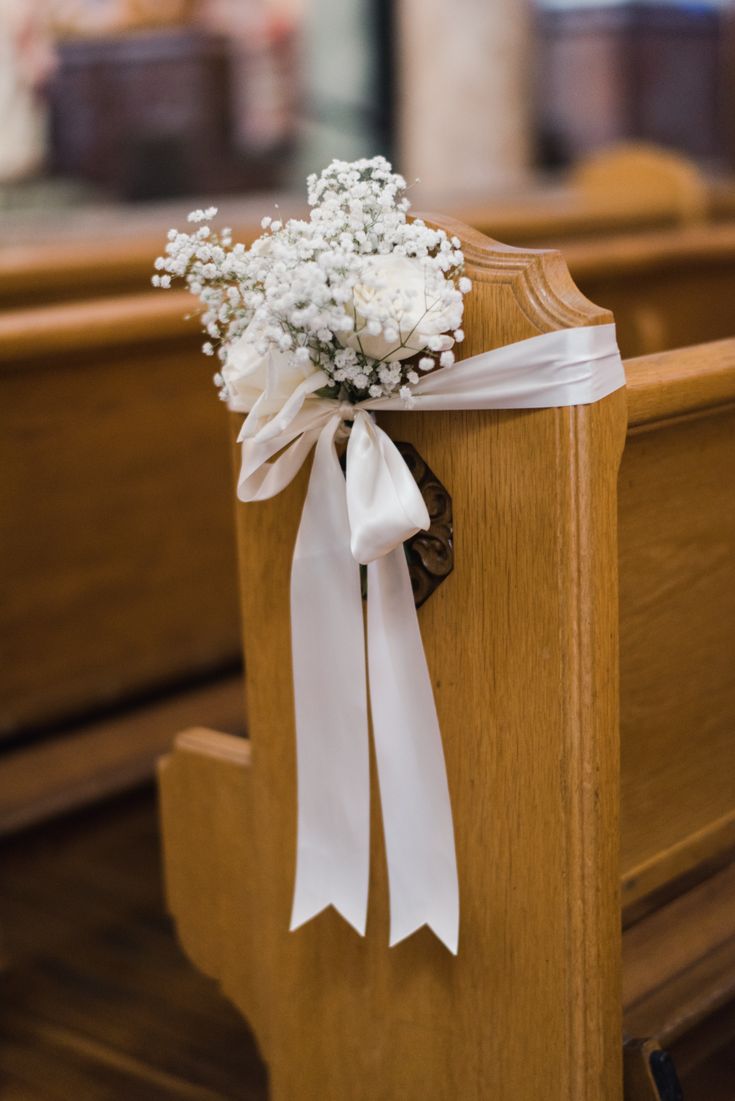 a bouquet of baby's breath sits on the pews of a wooden church