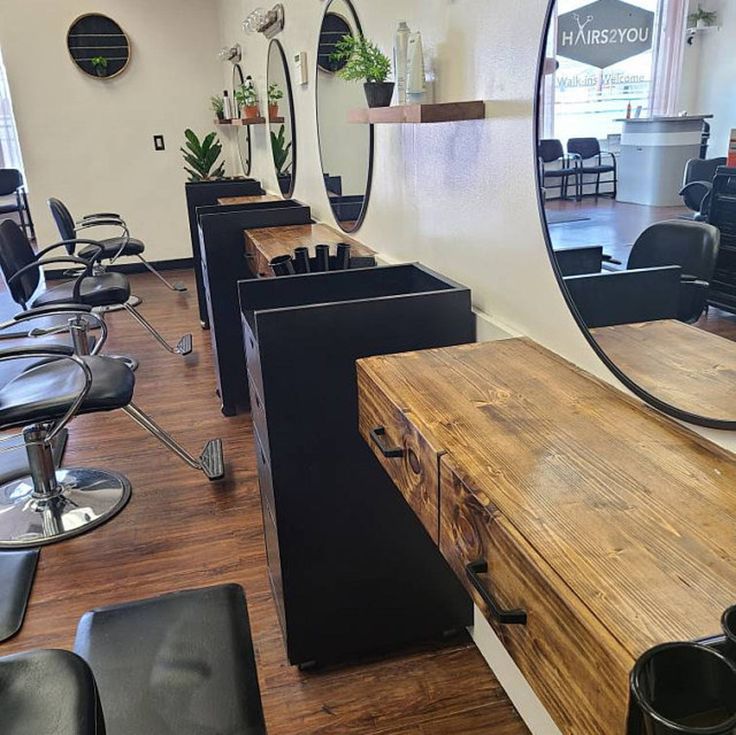 a hair salon with chairs and mirrors on the wall