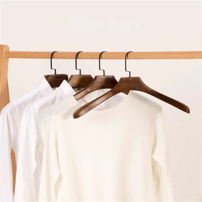 clothes hanging on wooden hangers in front of a white wall