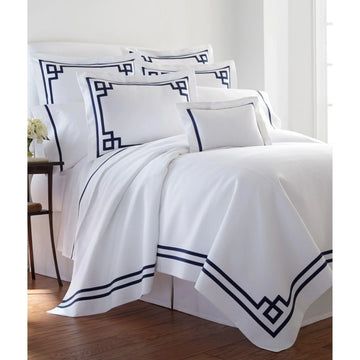 a bed with white sheets and black trimmings on the comforter is shown