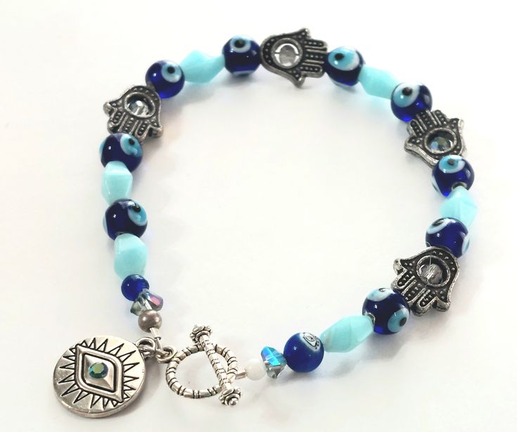 "Bracelet measures large at 9\" long. This handcrafted spiritual Hamsa eye beaded bracelet is a unique and meaningful piece of jewelry that combines artistry with spiritual symbolism. The Hamsa, also known as the Hand of Fatima or Hand of Miriam, is a symbol that is believed to provide protection from the evil eye and bring good fortune. The \"eye\" in this context could refer to the design of an eye often incorporated into the Hamsa symbol, representing protection and awareness. In summary, this handcrafted spiritual Hamsa and eye-beaded bracelet is a manually crafted piece of jewelry that embodies spiritual significance, featuring the Hamsa symbol with an eye motif, and composed of beads, possibly selected for their aesthetic appeal or symbolic meaning. Such a bracelet not only serves as Spiritual Round Beaded Crystal Bracelet For Festivals, Spiritual Crystal Round Beads Bracelet For Festival, Spiritual Crystal Bracelet With Round Beads For Festival, Symbolic Beaded Bracelets With 8mm Beads, Handmade Spiritual Crystal Bracelet With Round Beads, Handmade Spiritual Stretch Bracelet For Festivals, Symbolic Handmade Bracelets For Festivals, Spiritual Stretch Bracelet With 8mm Beads For Festivals, Bohemian Evil Eye Bracelet For Festivals