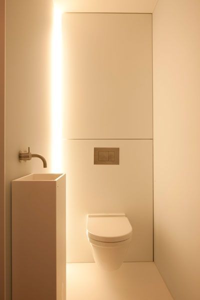 a white toilet sitting in a bathroom next to a wall mounted faucet with lights on it