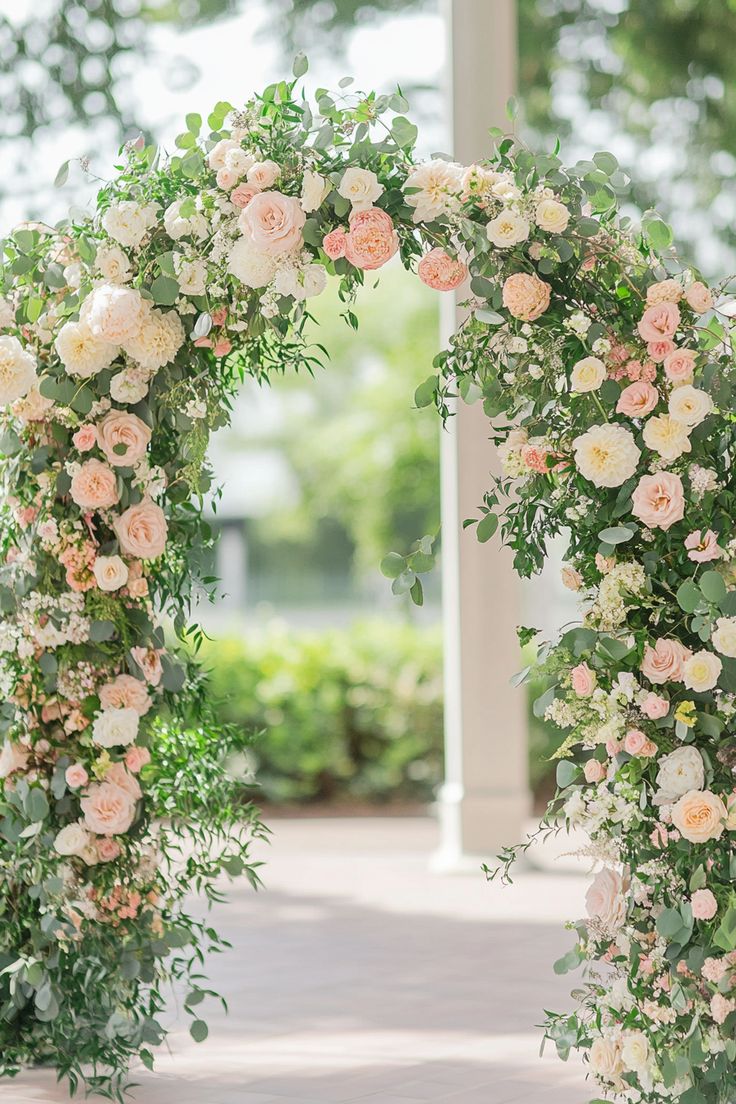 an archway decorated with flowers and greenery in the middle of a walkway area at a wedding