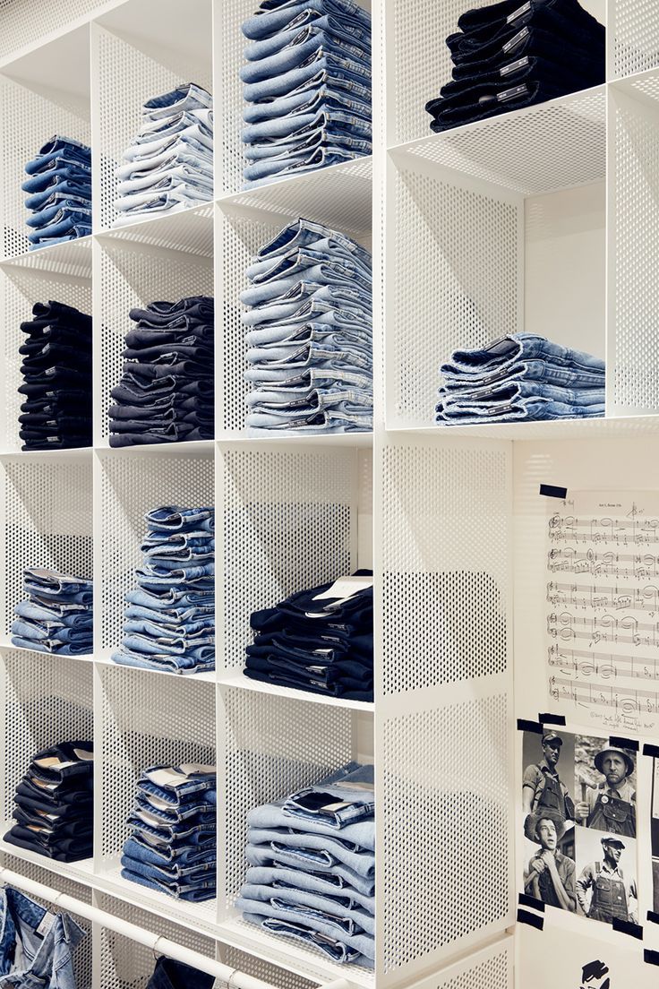 a white shelf filled with lots of blue jeans