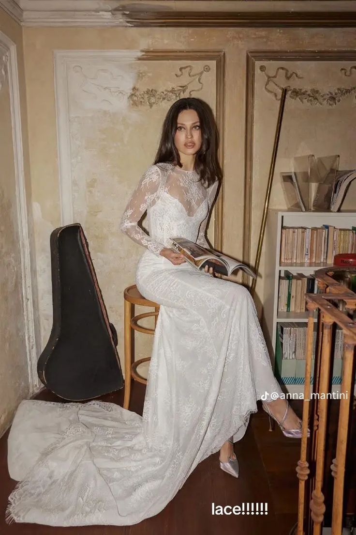 a woman in a white dress sitting on a chair with a guitar case behind her