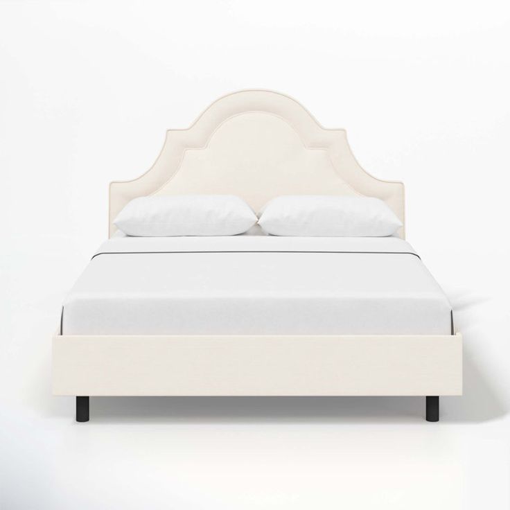 a bed with white linens and pillows on it's headboard is shown