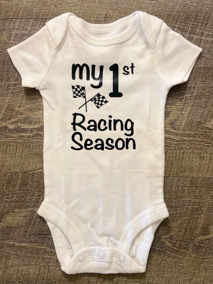 My 1st Racing Season This listing is for one (1) white bodysuit  with black lettering on the front. Available in short sleeve.  Available Sizes:  Newborn 3 Month 6 Month  9 Month  12 Month I hand make each bodysuit, no two will be exactly the same, please allow 3-7 business days for production. Please email me with any questions.  Material: White 100% Cotton  Care Instruction: Inside out wash Tumble Dry Do not bleach Do not iron directly onto the design Do not dry clean Want to see more, check u White Cotton Sports Bodysuit, White Sports Onesie With Letter Print, Sporty White Cotton Bodysuit, White Cotton Sporty Bodysuit, Casual Sports Onesie With Short Sleeves, Casual Short Sleeve Bodysuit For Sports, Casual Short Sleeve Sports Bodysuit, White Casual Bodysuit For Sports, White Casual Sports Bodysuit