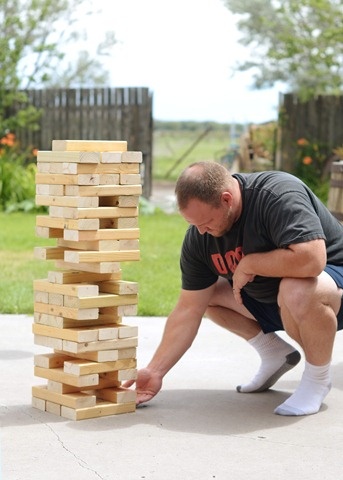 a man kneeling down next to a stack of wooden blocks