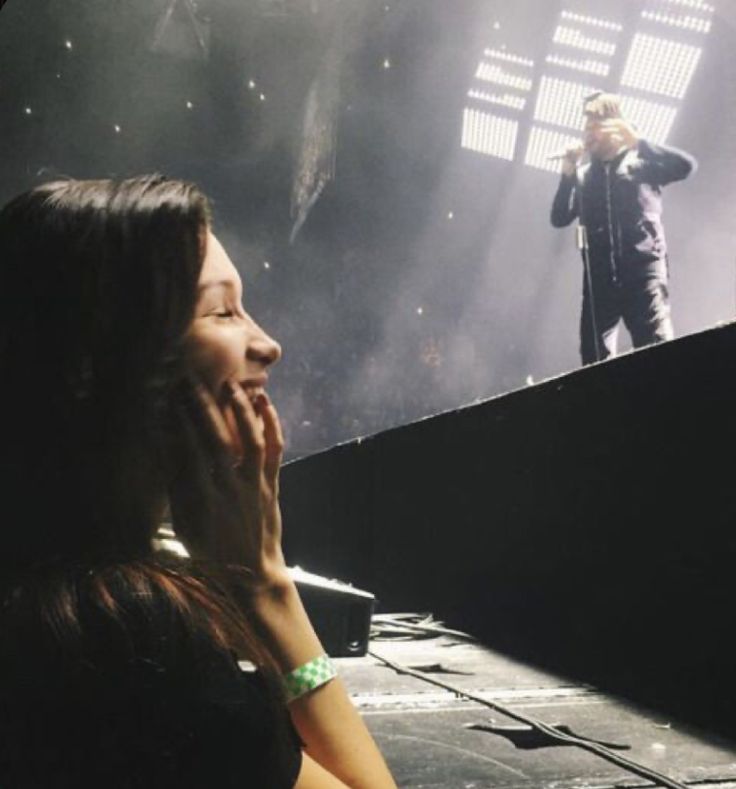 a woman is talking on her cell phone while standing in front of a stage with lights