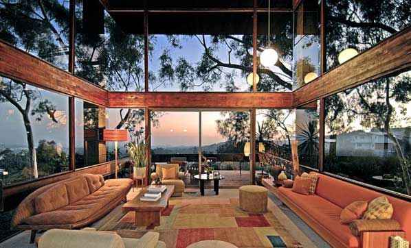 a living room filled with lots of furniture and large windows overlooking the city at sunset