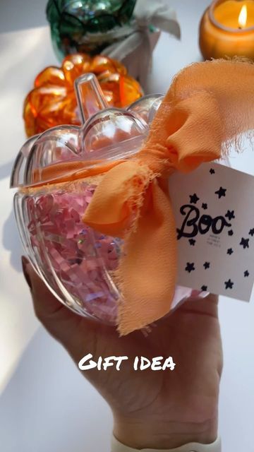 a hand holding a glass bowl filled with candies and a tag that says boo gift idea