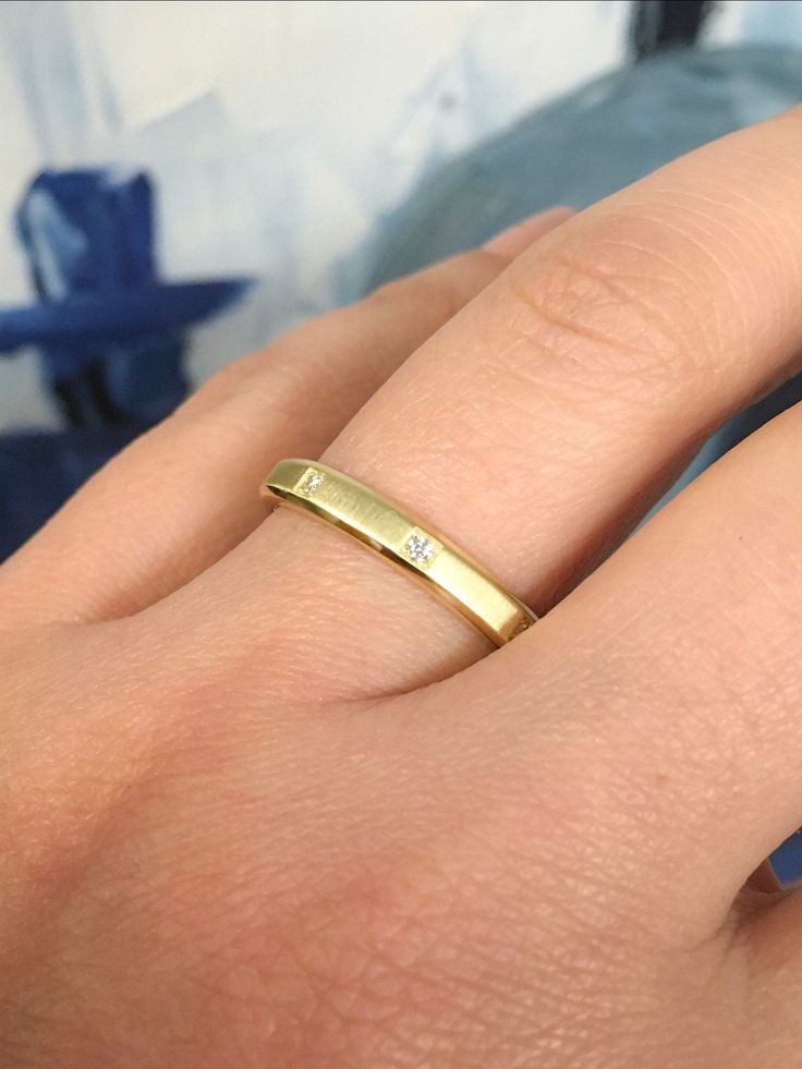 a woman's hand with a yellow gold ring on her left finger, and a diamond in the middle