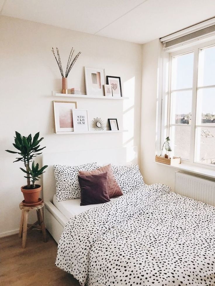 a bedroom with a bed, potted plant and window in the corner next to it