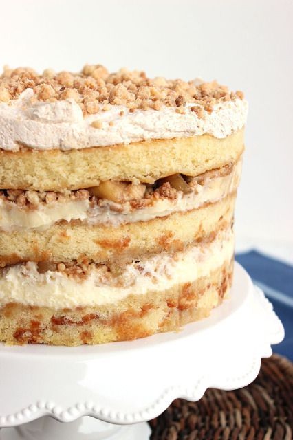 a layered cake with white frosting and walnuts on top sits on a plate