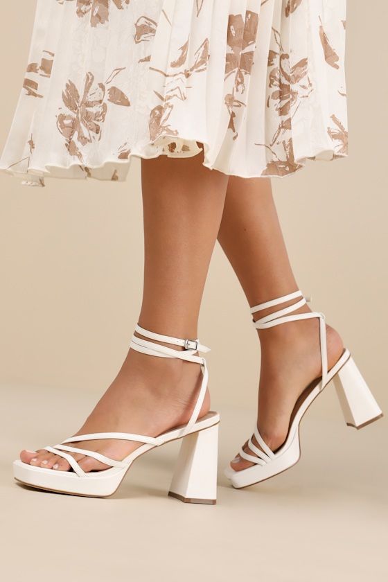 Complete your OOTN to perfection with a little help from the Lulus Antonnia White Strappy High Heel Ankle Wrap Sandals! Smooth faux leather shapes these iconic heels that feature a square footbed and a strappy, asymmetrical upper (all atop a 0.75"" toe platform). Long slender straps sprout from the sides to wrap around the ankle and secure with a silver buckle. A sculpted, sky-high block heel completes the look! 3. 75" wrapped block heel. Lightly cushioned insole. Rubber sole has nonskid markings. Man made materials. Imported. Lulus | Antonnia White Strappy High Heel Ankle Wrap Sandal Heels | Size 8.5. Chic Sandals With Stacked Heel For Wedding, Chic Square Toe Platform Sandals, Formal Platform Sandals With Square Toe, White Square Toe Sandals With Stacked Heel, Formal Square Toe Platform Sandals, Luxury Stacked Heel Block Heels For Summer, Chic Sandals With Heel Loop And Block Heel, Luxury Block Heels With Stacked Heel For Summer, Modern Heels For Spring Wedding