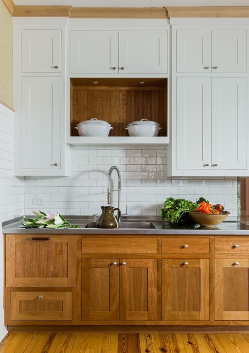 a kitchen with white cabinets and wooden floors is pictured in this image, there are bowls on the counter