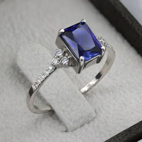 An impressive radiant cut Sapphire brings rich color to this ring, contrasted by brilliant diamond side stones set in a shimmering 10,14 or 18 Karat gold setting.- Made to Order, Perfectly finished, Fast shipping fully insured and trackable online.- Gemstone info: Sapphire corundum 8x6 mm, Excellent cut, 1.54 ct- Diamond info: 16 x Diamonds ranging from 1-1.75mm, VS-E, 0.15 ctw- Arrives gift ready with a certificate of authenticity Luxury Diamond Ring With Rectangular Stone, Classic Cubic Zirconia Radiant Cut Sapphire Ring, Formal Emerald Ring With Diamond And Rectangular Stone, Rectangular Emerald Ring With Brilliant Cut Diamond, Formal Emerald Ring With Rectangular Diamond, Luxury Diamond Ring With Rectangular Stone For Anniversary, Rectangular Brilliant Cut Sapphire Ring For Formal Occasions, Luxury Square Cut Sapphire Ring With Prong Setting, Formal Radiant Cut Cluster Ring In Fine Jewelry Style