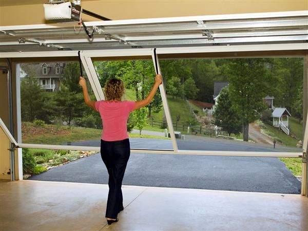 a woman standing in front of an open garage door with her arms up and hands behind her head