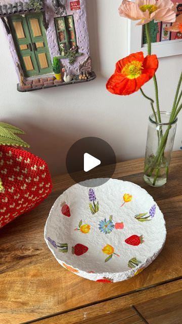 a vase with flowers in it sitting on a table next to a plate that has been painted