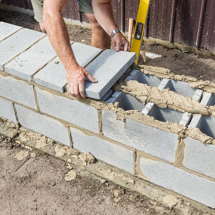 a man laying bricks on the ground