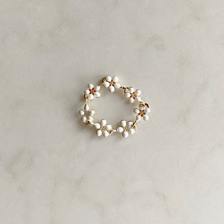 a bracelet with white pearls and gold beads on a marble surface, close up view