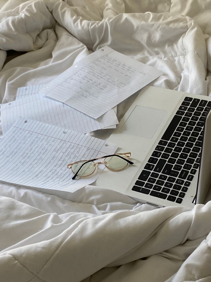 an open laptop computer sitting on top of a bed covered in white sheets and blankets