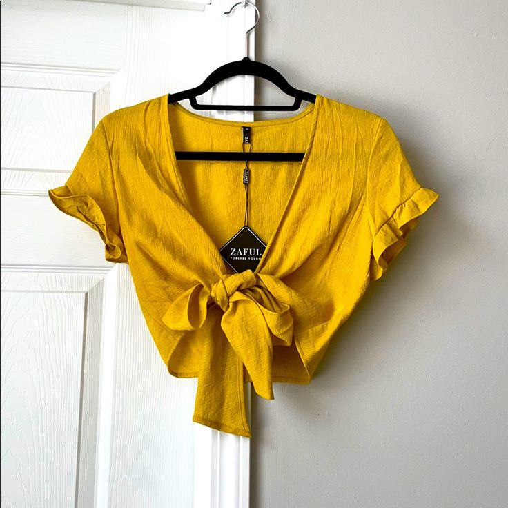 Yellow Tied Cropped Blouse, So Many Different Ways To Tie And Wear This Shirt The Options Are Endless! Loose, Tight, High, Low, Bow In Front, Knot In Back, Really Anyway! Size Medium But Fits Any Size S-L Because It Is Adjustable New With Tags, Never Worn, Great Yellow (Almost Mustard But Not So Dark) Color Summer V-neck Tied Tops, Summer Top With Tie Waist For Brunch, Summer Tops With Tied Detail For Day Out, Tied Tops For Spring Vacation, Spring Vacation Tied Top, Summer Tie Waist Blouse For Day Out, Fitted Tie Waist Top For Brunch, Fitted Tops With Tie Waist For Brunch, Fitted Top With Tie Waist For Brunch