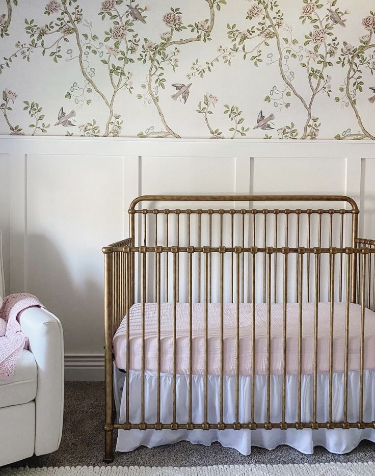 a baby's crib in the corner of a room with floral wallpaper