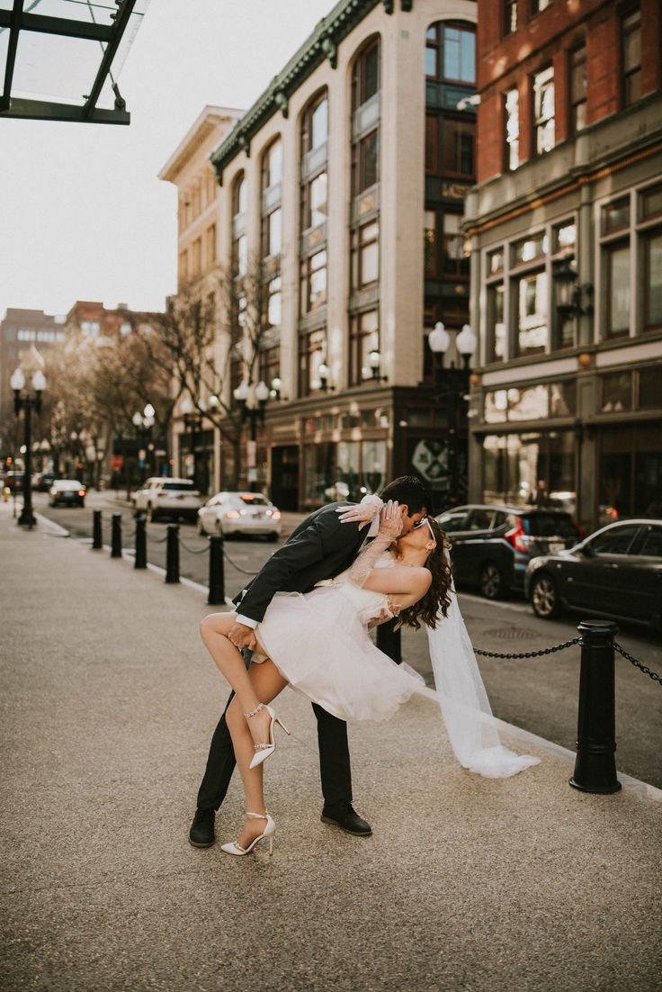 a bride and groom kissing on the street