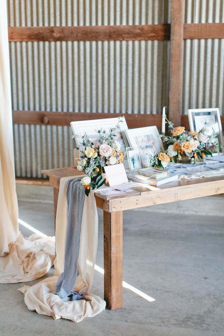 a wooden table topped with pictures and flowers on top of a white cloth covered floor