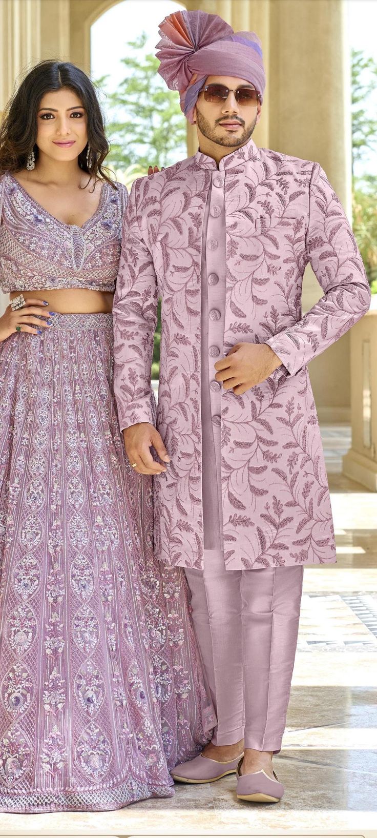 a man and woman standing next to each other in front of an archway wearing purple outfits