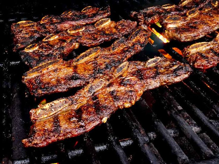 several steaks are cooking on the grill