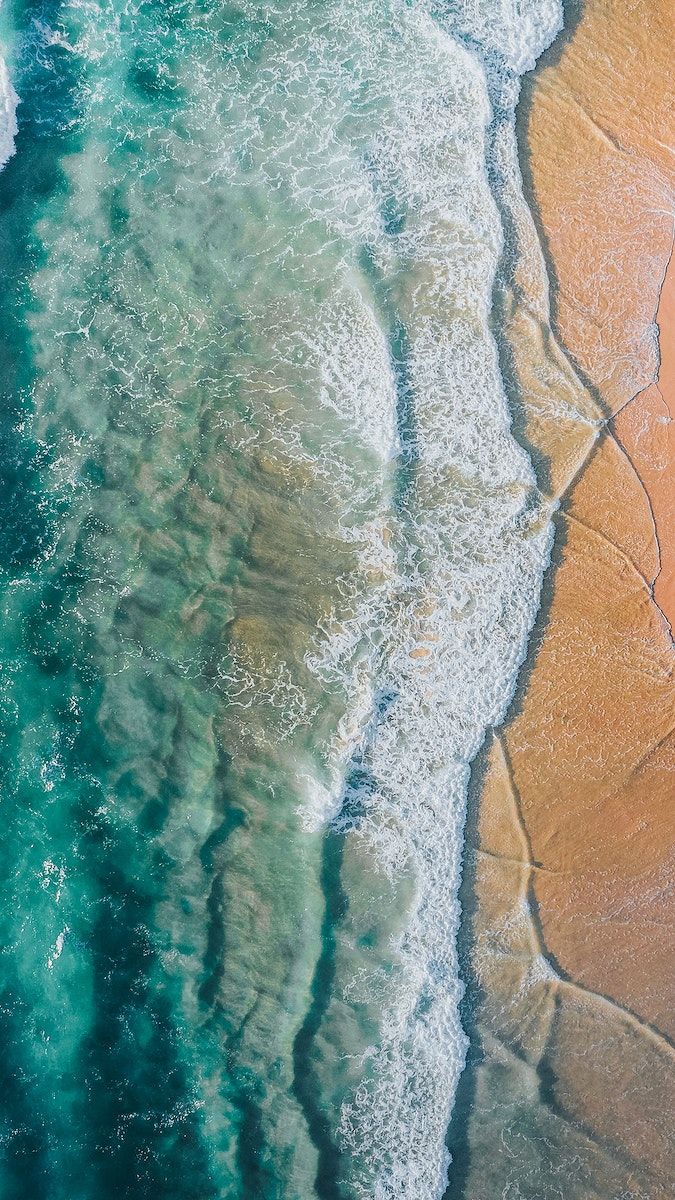 an aerial view of the ocean and sand