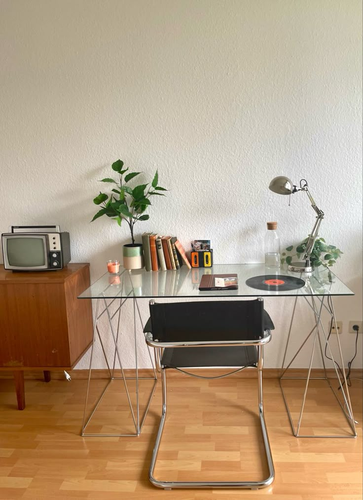 a glass desk with a record player on it and a plant in front of it