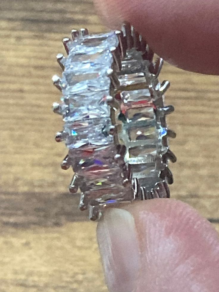 someone is holding up a ring made out of crystal stones and silver metal wire on a wooden surface