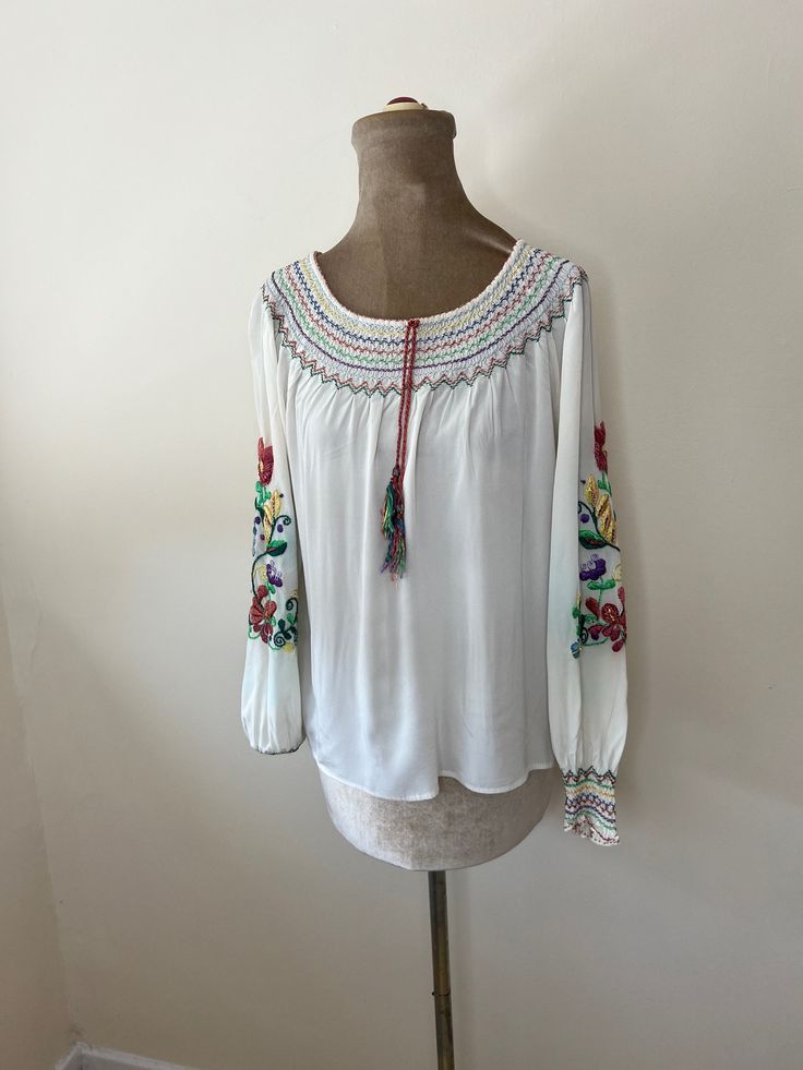 A vintage embroidered folk blouse. It has multicoloured tassels and floral embroidery. Finished with French seams. The embroidery has some colour run. UK Size 8 - 10. Please check measurements: Chest - 108cm Waist - 102cm Length - 56cm Peasant Style Embroidered Top With Floral Embroidery For Fall, Bohemian Long Sleeve Blouse With Floral Embroidery, Peasant Style Embroidered Top With Floral Details For Fall, Long Sleeve Peasant Top With Multicolor Embroidery For Festival, Bohemian Spring Blouse With Intricate Embroidery, Bohemian Spring Tops With Embroidered Border, Bohemian Tops With Embroidered Border For Spring, Bohemian Blouse With Intricate Embroidery For Spring, Multicolor Embroidered Long Sleeve Peasant Top For Festivals