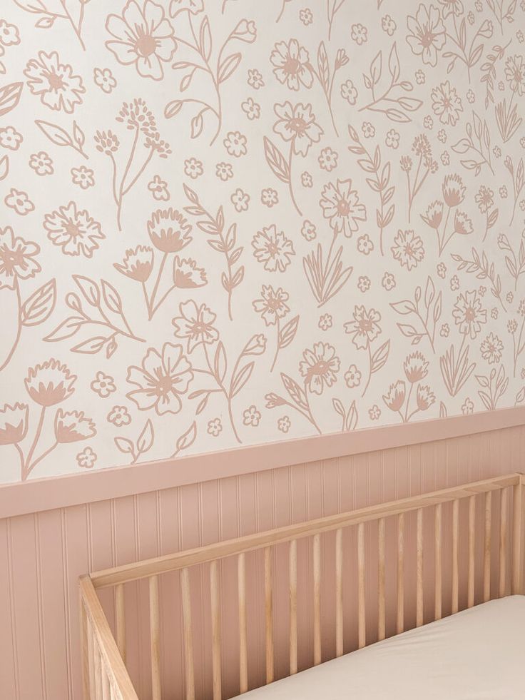 a baby's crib in front of a floral wallpaper