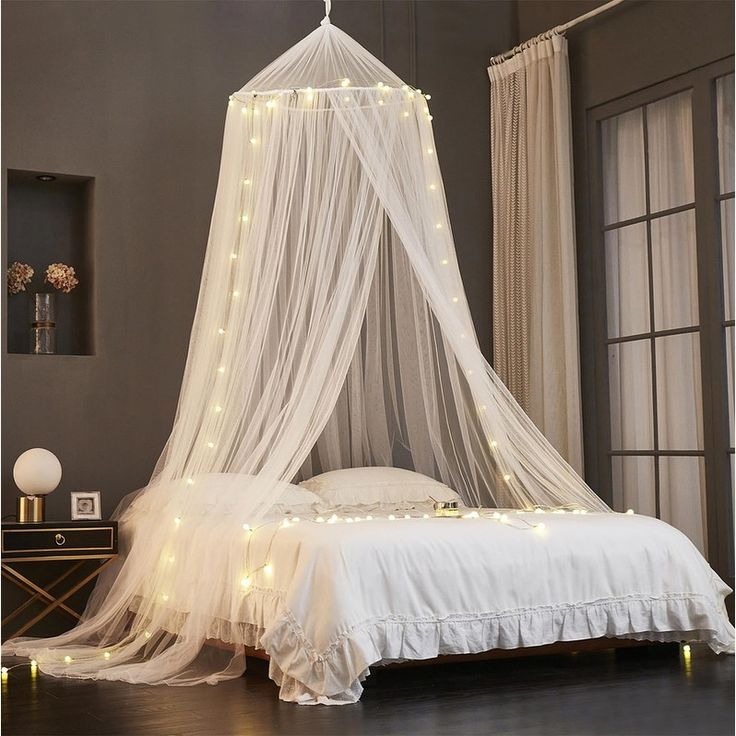 a canopy bed with white netting and fairy lights