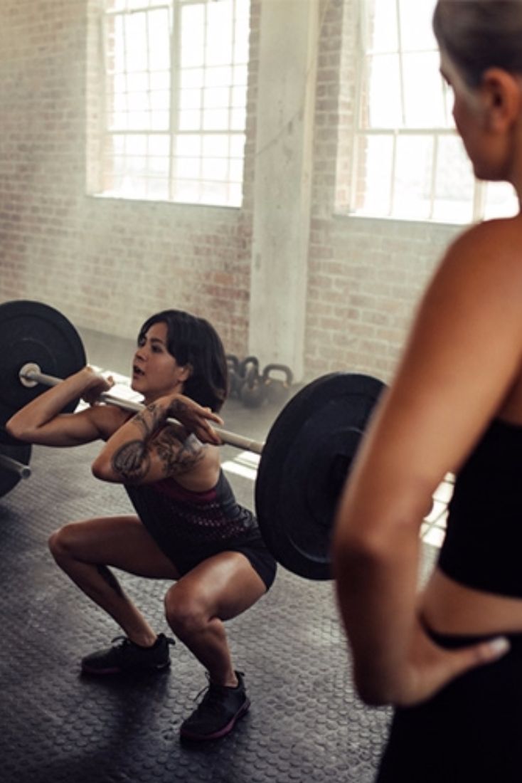 a group of people in a gym doing squats with barbells on their backs