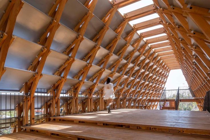 a person is walking up some stairs in a large building with wooden beams on it