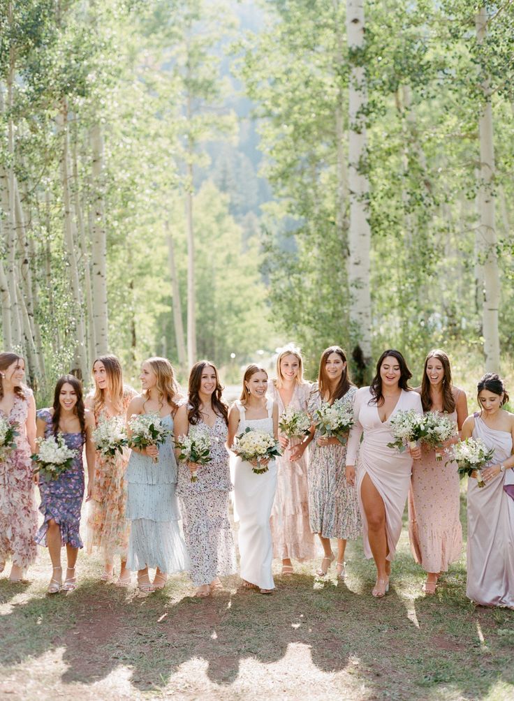 a group of women standing next to each other in front of some trees and flowers