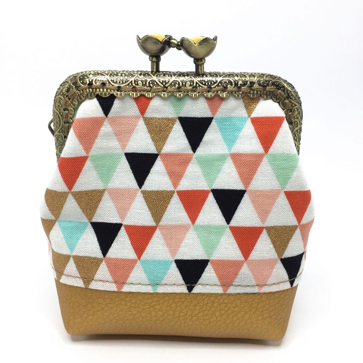 a small purse with two birds on it's handle and colorful triangle print fabric