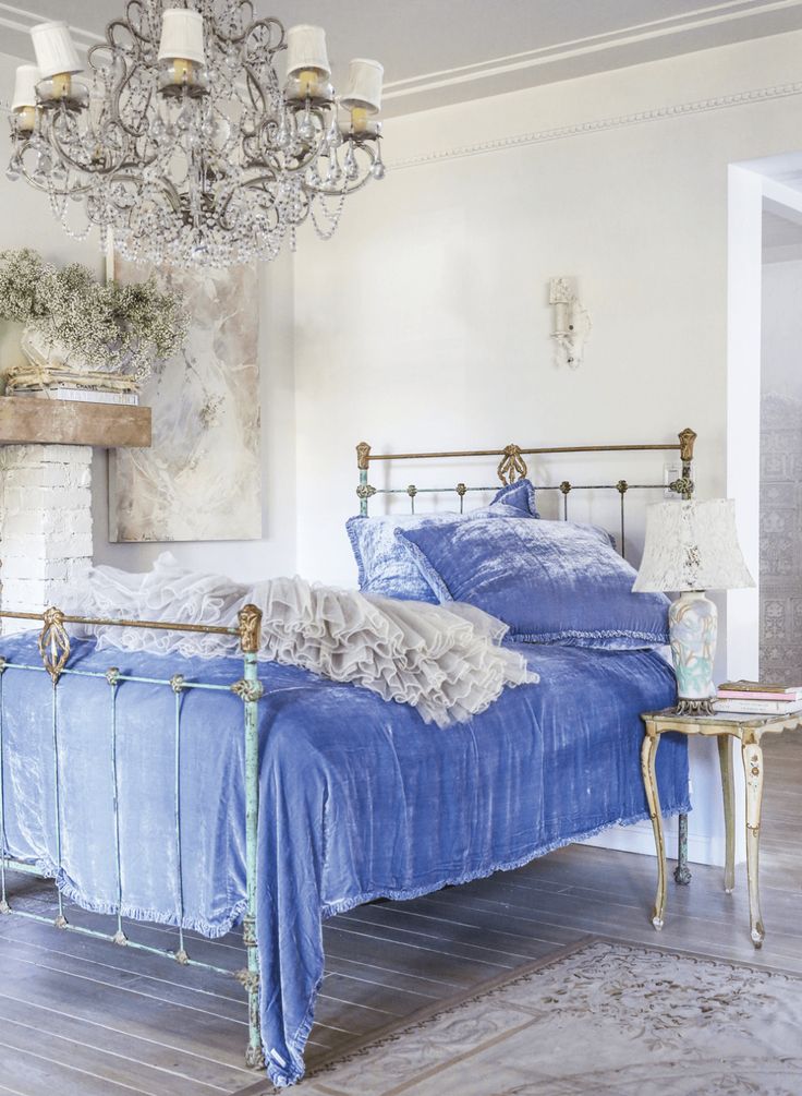 a bedroom with a blue bed and chandelier