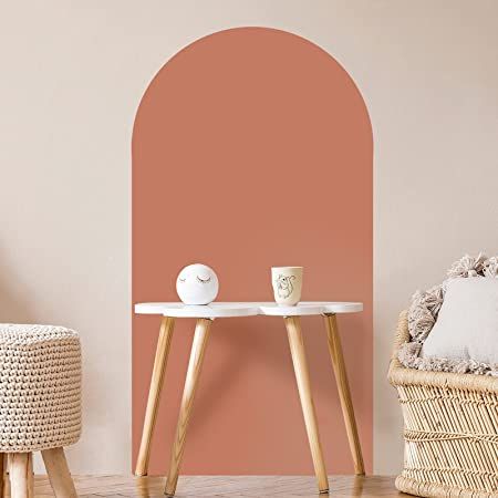 two small tables with cups on them in front of a pink wall and wicker chair