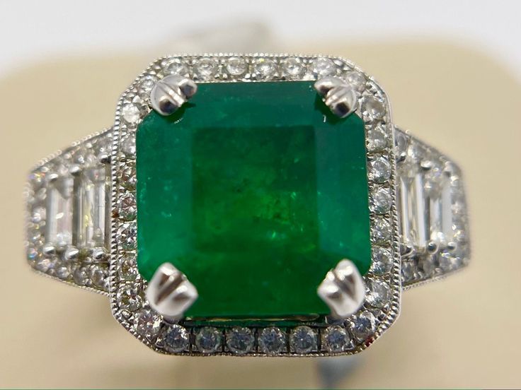 A one of a kind ring you don't see often. The square-cut emerald on this ring weighs in at 6.29 ct and you have the diamonds that total at 1.50 ct. The ring also holds 18 ct of white gold and 18 ct of yellow gold. Please contact us with any questions. Rectangular Emerald Ring With Brilliant Cut Diamond, Gia Certified Luxury Square Cut Emerald Ring, Luxury Gia Certified Square Cut Emerald Ring, Luxury Square Cut Green Emerald Ring, Luxury Emerald Ring With Square Cut Diamond, Luxury Square Cut Diamond Emerald Ring, Luxury Square-cut Emerald Ring With Diamonds, Luxury Square Cut Emerald Ring With Diamonds, Fine Jewelry Green Diamond Ring With Square Cut