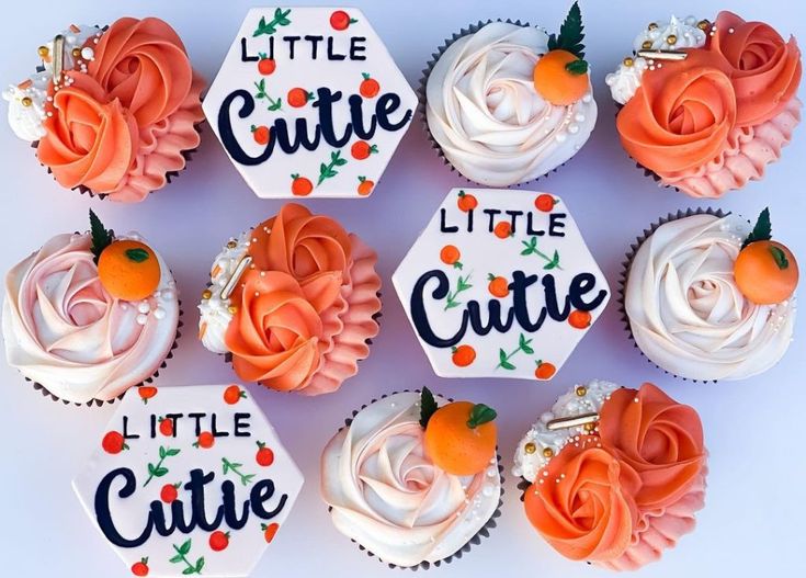 cupcakes decorated with orange and white frosting are arranged in the shape of he little cutie