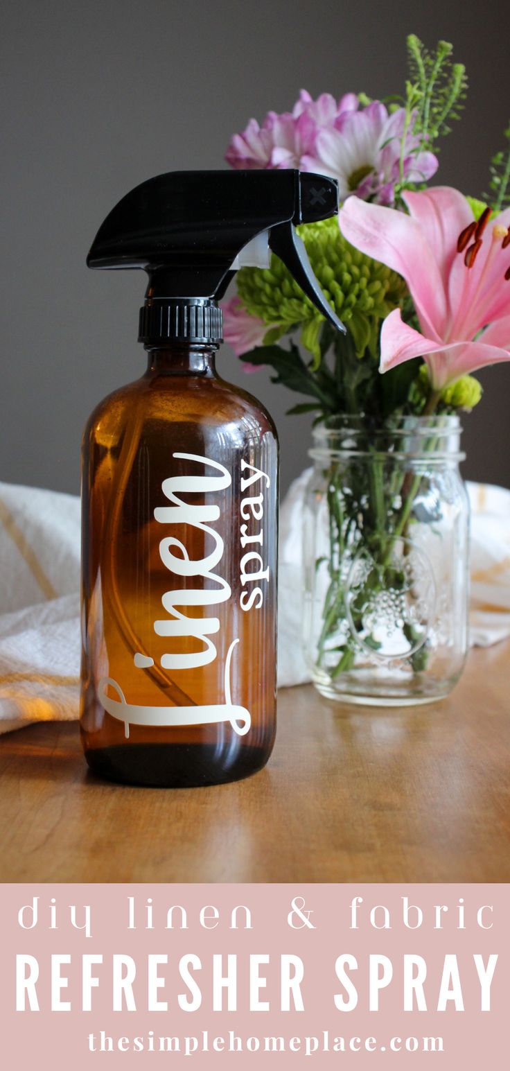 a bottle of liquid sitting on top of a table next to a vase with flowers