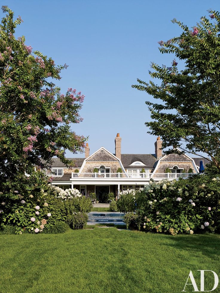 a large white house surrounded by trees and flowers